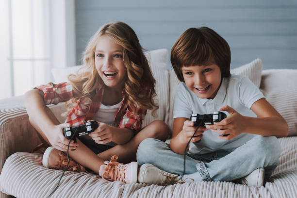 Joyful children with game controllers play video games at home. Kid's leisure.