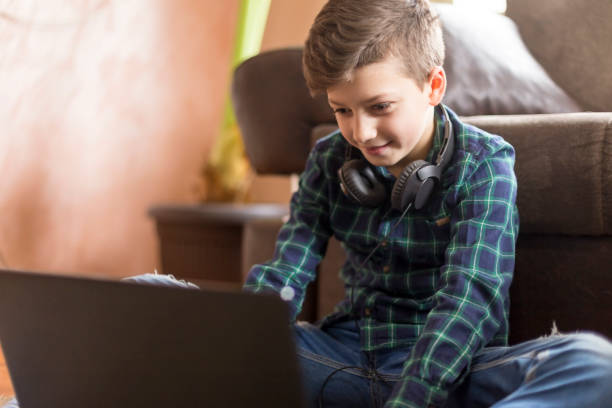 Boy playing video games on laptop while wearing headphones